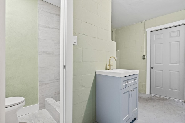 bathroom featuring vanity, concrete flooring, and toilet