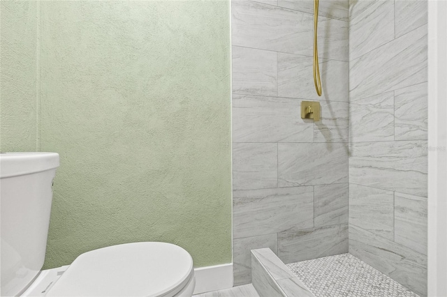 bathroom featuring a tile shower and toilet