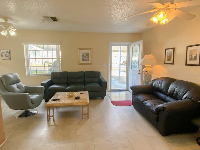 tiled living room featuring ceiling fan, a healthy amount of sunlight, and a textured ceiling