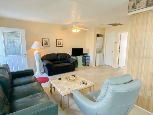 living room with ceiling fan and stacked washer / drying machine