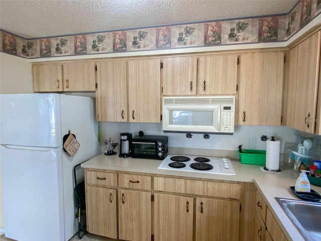 kitchen with white appliances, light brown cabinetry, sink, and a textured ceiling