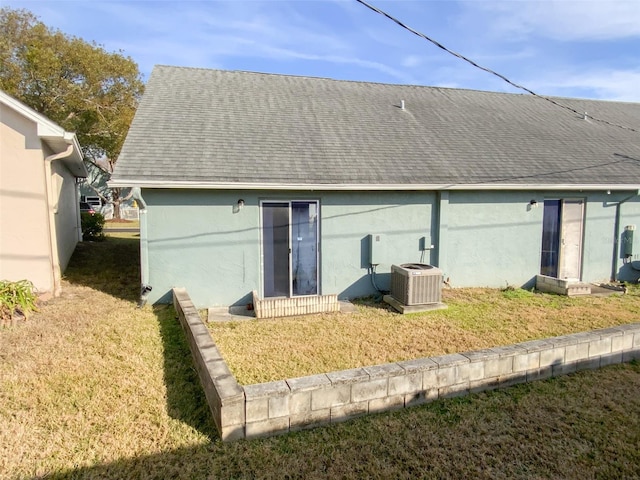 rear view of house featuring cooling unit and a lawn