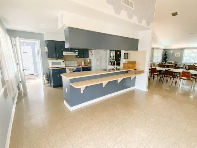 kitchen featuring blue cabinets, sink, a kitchen bar, kitchen peninsula, and white appliances