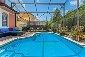 view of swimming pool with outdoor lounge area and glass enclosure