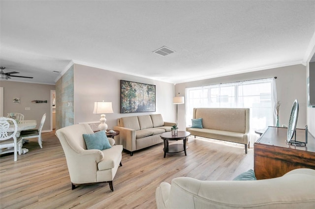 living room with light hardwood / wood-style floors, a textured ceiling, and ornamental molding