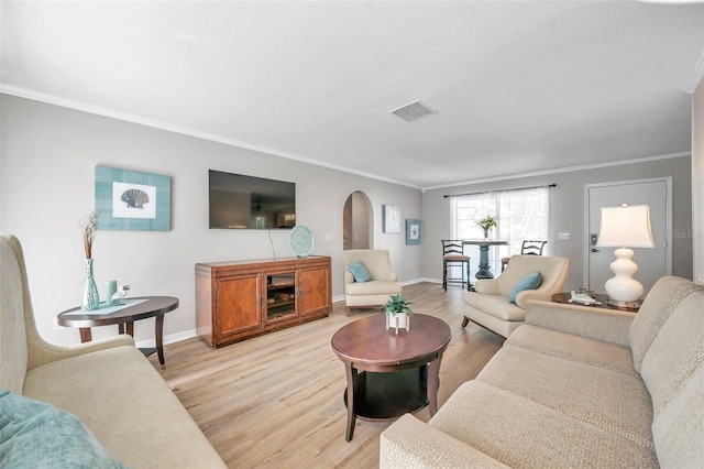 living room with light hardwood / wood-style flooring, a textured ceiling, and ornamental molding