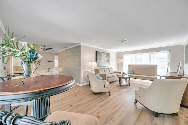 living room with light wood-type flooring, ornamental molding, and ceiling fan