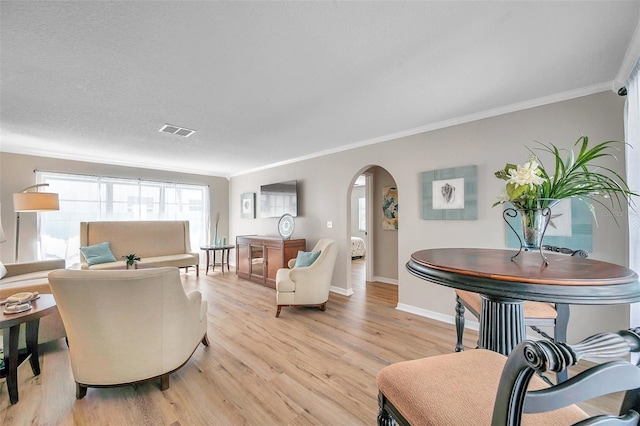 living room featuring light hardwood / wood-style flooring, a textured ceiling, and ornamental molding