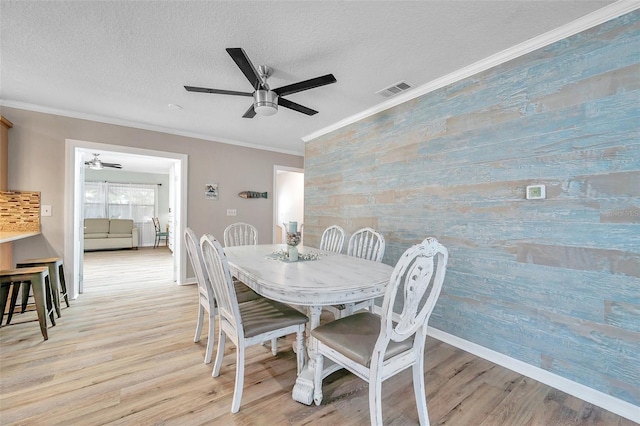 dining room with light hardwood / wood-style floors, a textured ceiling, ceiling fan, and ornamental molding