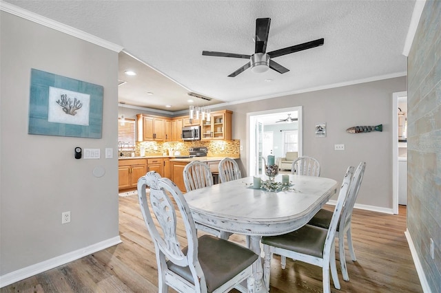 dining space with light hardwood / wood-style floors, crown molding, and a textured ceiling