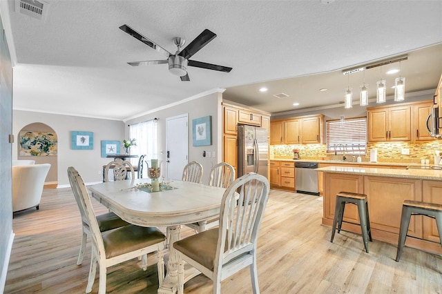 dining room with ceiling fan, ornamental molding, light hardwood / wood-style floors, and a textured ceiling