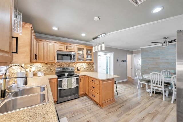 kitchen with sink, pendant lighting, stainless steel appliances, kitchen peninsula, and a breakfast bar area