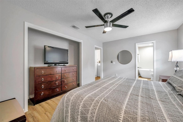 bedroom featuring ensuite bathroom, light hardwood / wood-style flooring, ceiling fan, and a textured ceiling