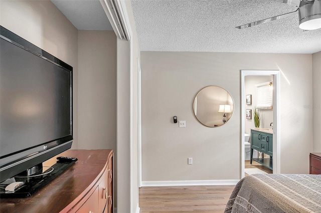 bedroom featuring light hardwood / wood-style floors, connected bathroom, and a textured ceiling