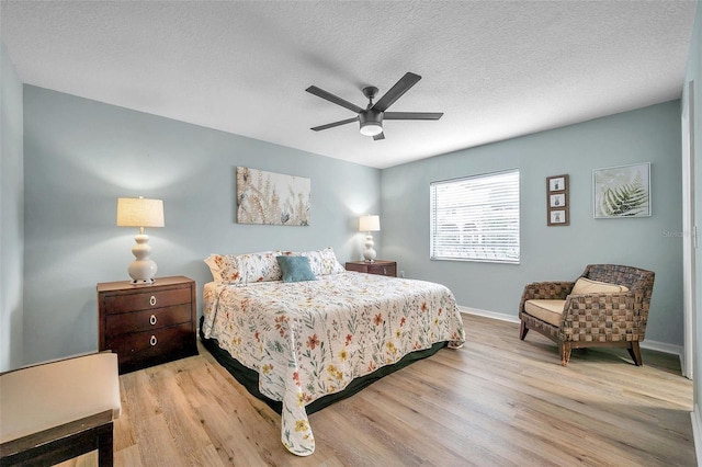 bedroom with ceiling fan, light hardwood / wood-style floors, and a textured ceiling