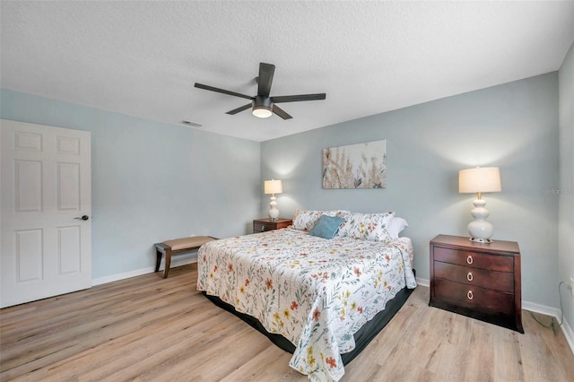 bedroom with light hardwood / wood-style floors, ceiling fan, and a textured ceiling