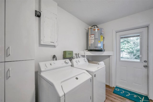 laundry area with washer and dryer, electric water heater, a textured ceiling, and light hardwood / wood-style flooring