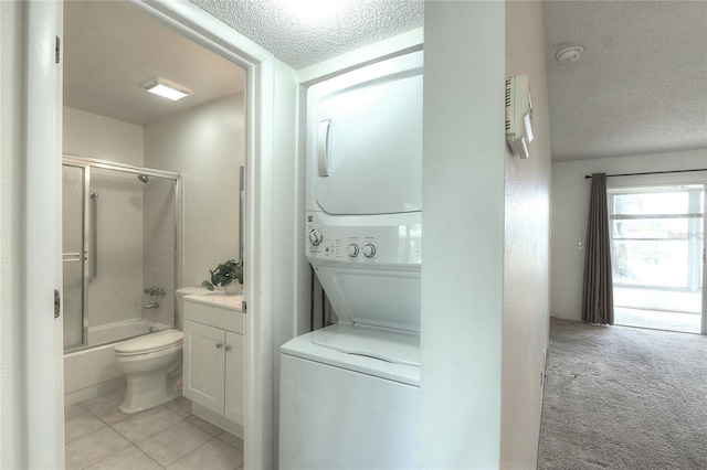 full bathroom with combined bath / shower with glass door, vanity, stacked washer / drying machine, a textured ceiling, and toilet