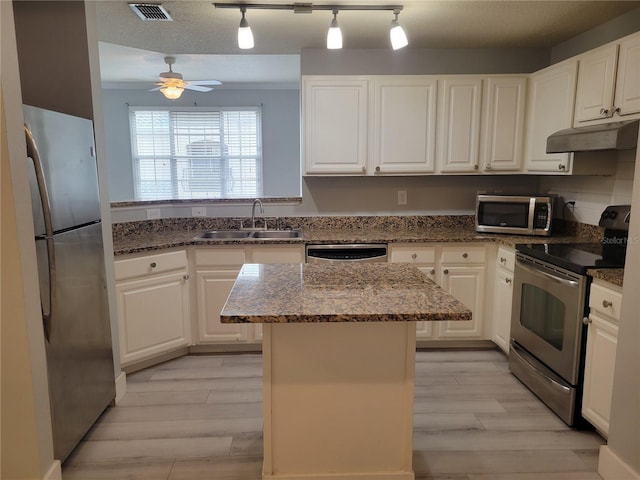 kitchen featuring sink, white cabinetry, a center island, appliances with stainless steel finishes, and dark stone counters