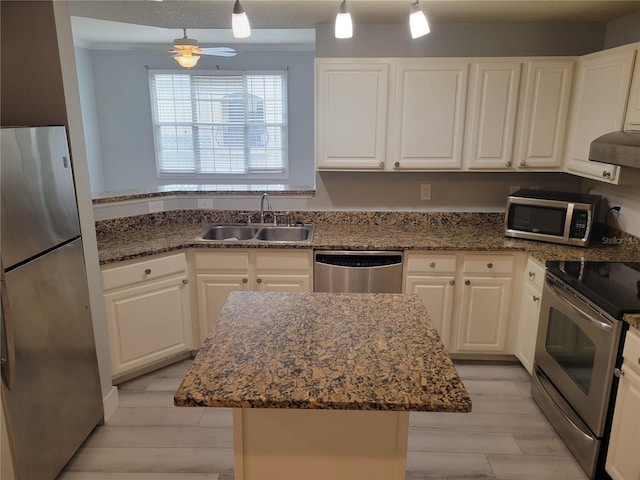 kitchen featuring decorative light fixtures, white cabinetry, sink, a center island, and stainless steel appliances