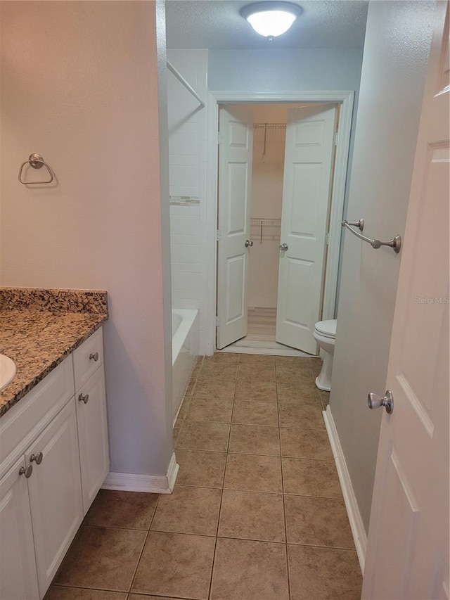 bathroom with tile patterned flooring, vanity, a textured ceiling, and toilet