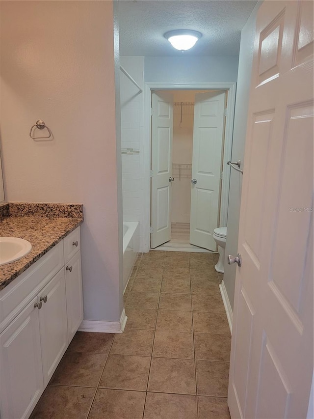 bathroom featuring vanity, tile patterned floors, a textured ceiling, and toilet