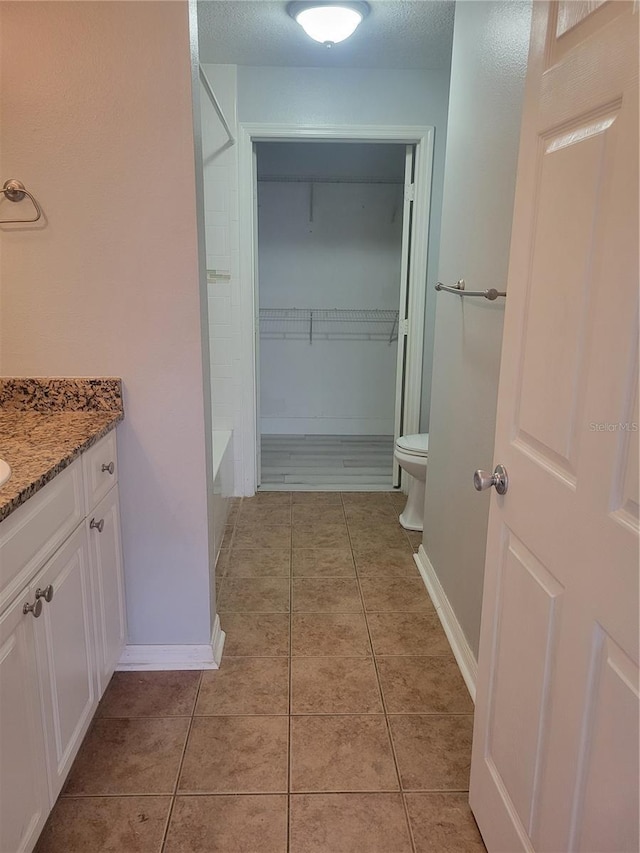 bathroom featuring vanity, toilet, tile patterned flooring, and a textured ceiling