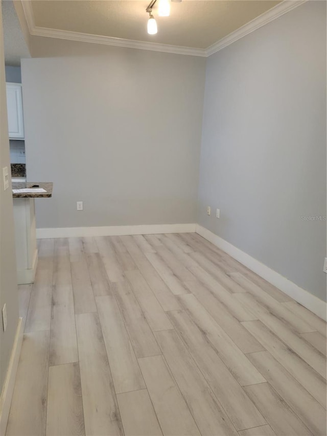 empty room featuring crown molding, track lighting, and light hardwood / wood-style floors