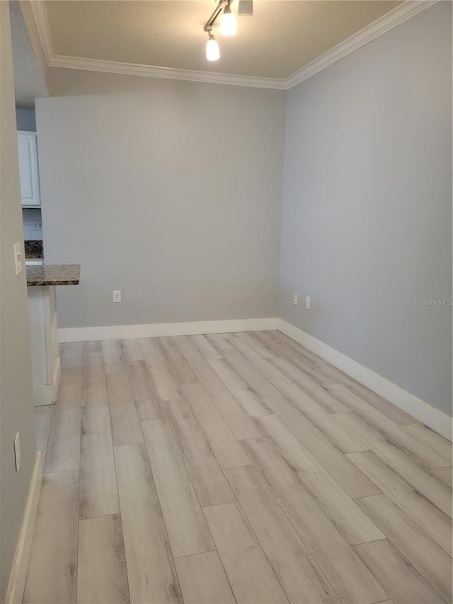 empty room with crown molding, light hardwood / wood-style floors, and a textured ceiling