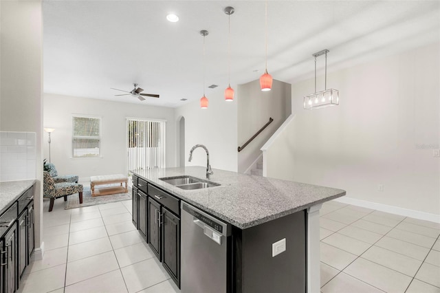 kitchen featuring sink, a center island with sink, light tile patterned flooring, decorative light fixtures, and stainless steel dishwasher