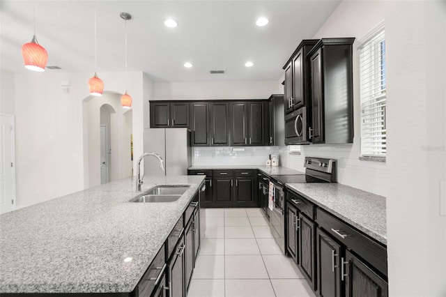 kitchen with a large island, sink, appliances with stainless steel finishes, decorative backsplash, and decorative light fixtures