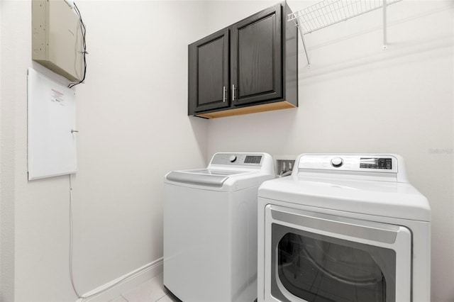 clothes washing area featuring light tile patterned flooring, cabinets, and washer and dryer