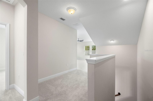 corridor featuring light carpet and a textured ceiling