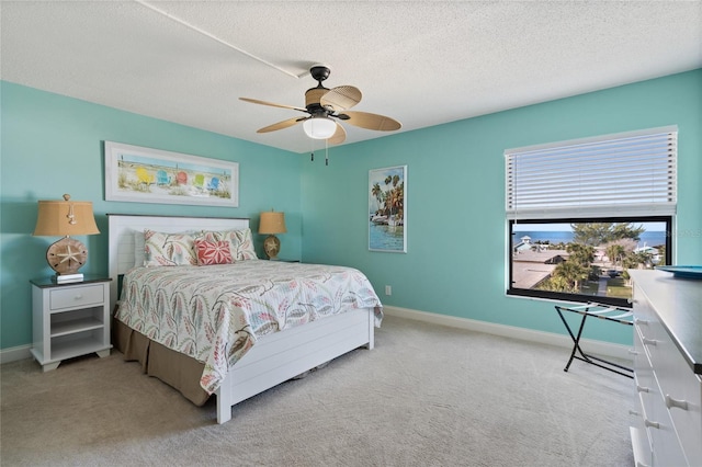 carpeted bedroom featuring ceiling fan and a textured ceiling