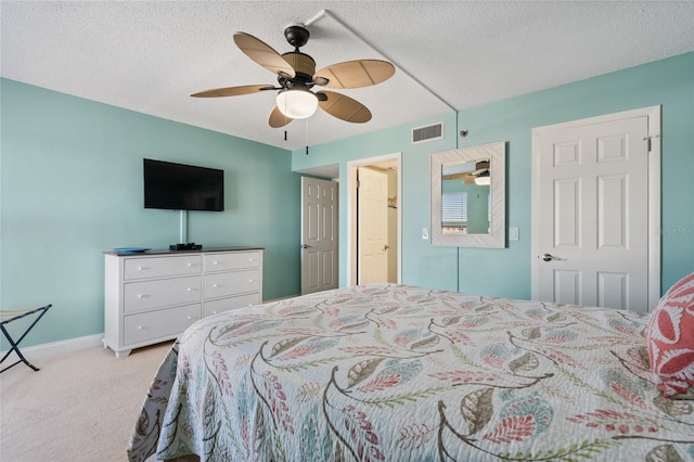 bedroom with ceiling fan, light colored carpet, and a textured ceiling