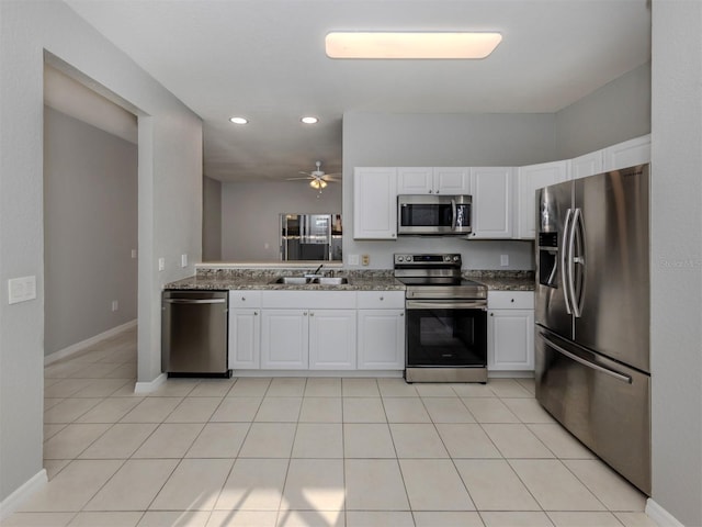 kitchen with appliances with stainless steel finishes, sink, white cabinets, and dark stone counters