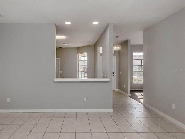 spare room with light tile patterned floors and an inviting chandelier