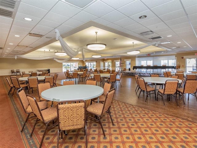 dining area featuring wood-type flooring and a paneled ceiling