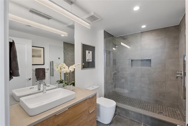 bathroom featuring vanity, a tile shower, tile patterned floors, and toilet