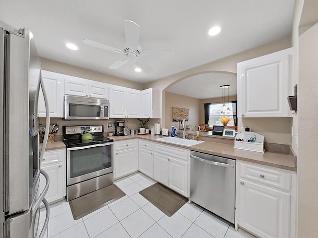 kitchen with decorative light fixtures, white cabinetry, sink, light tile patterned floors, and stainless steel appliances