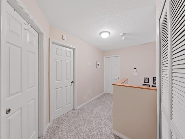 hall featuring light carpet and a textured ceiling