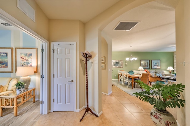 corridor featuring an inviting chandelier and light tile patterned floors