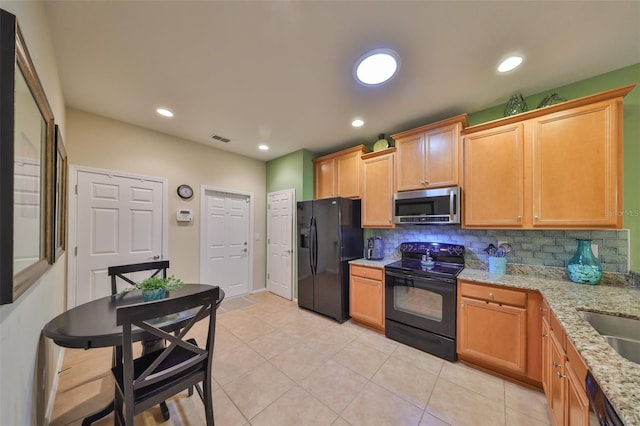 kitchen with light tile patterned flooring, light stone countertops, decorative backsplash, and black appliances