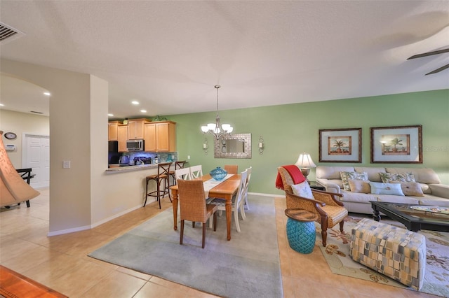 dining space with light tile patterned flooring, ceiling fan with notable chandelier, and a textured ceiling