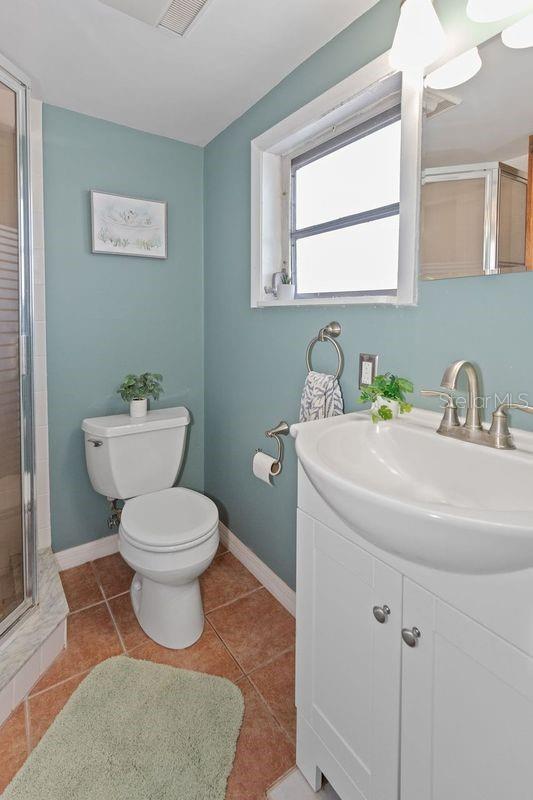 bathroom featuring tile patterned floors, toilet, a shower with door, and vanity