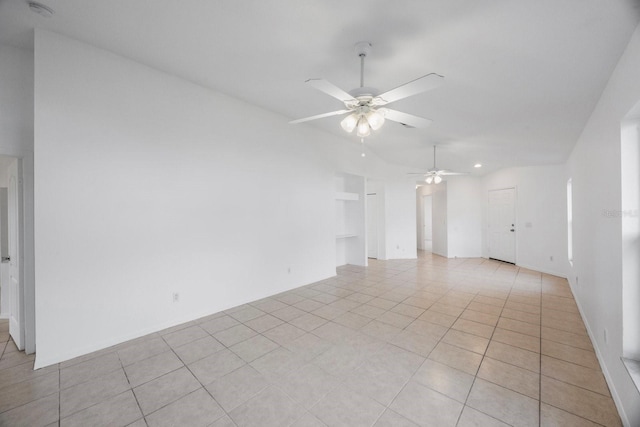 empty room with ceiling fan, vaulted ceiling, and light tile patterned floors