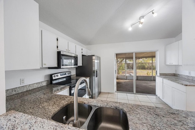 kitchen with sink, white cabinetry, vaulted ceiling, light tile patterned floors, and appliances with stainless steel finishes