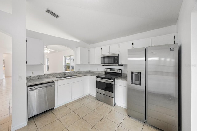 kitchen with lofted ceiling, sink, stainless steel appliances, white cabinets, and light tile patterned flooring