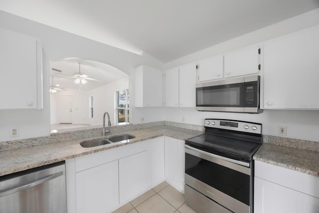 kitchen featuring appliances with stainless steel finishes, white cabinetry, sink, light tile patterned floors, and ceiling fan