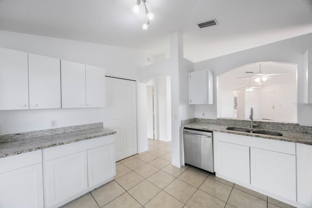 kitchen featuring vaulted ceiling, white cabinetry, sink, stainless steel dishwasher, and light stone countertops